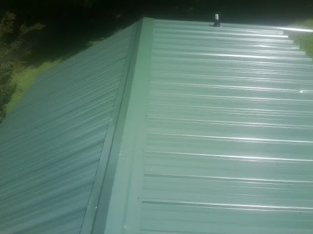 New green metal panels meeting at the ridge of a roof — Flat Roof Repair work by our crew in Rimrock
