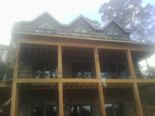 Dormers and porch framing on a large log home under construction — Roof Coating work by our crew in Rimrock