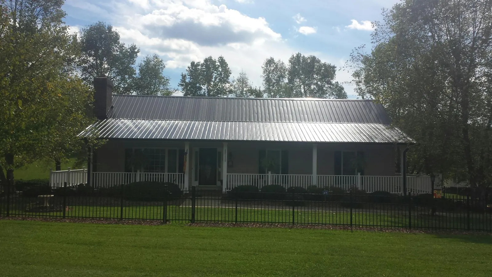 Gray metal roof on a brick ranch with a full width front porch — Gutter Guard Installation work by our crew in Rimrock