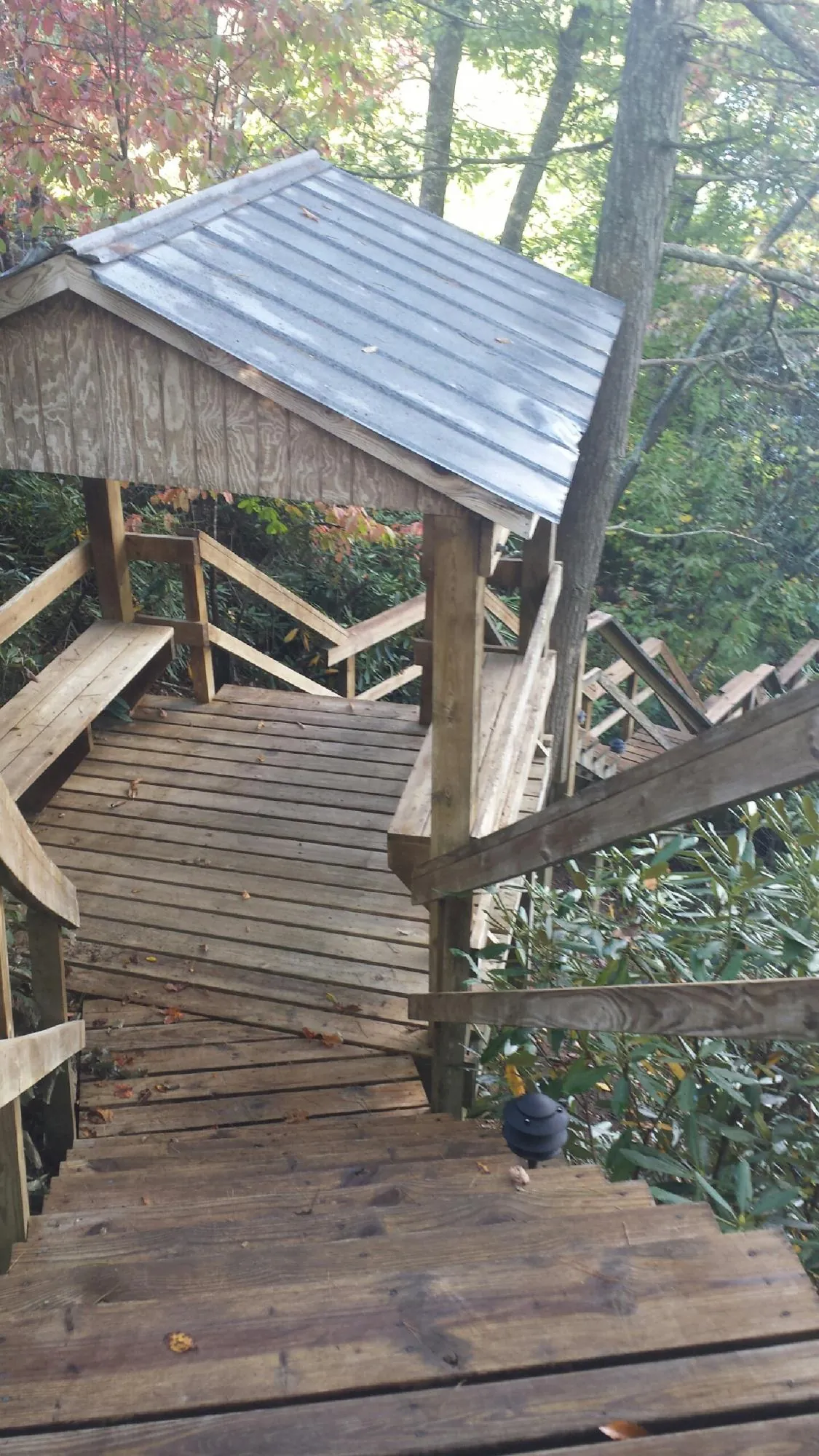 Metal roofed shelter over wooden steps on a wooded walkway — Skylight Repair & Installation work by our crew in Rimrock