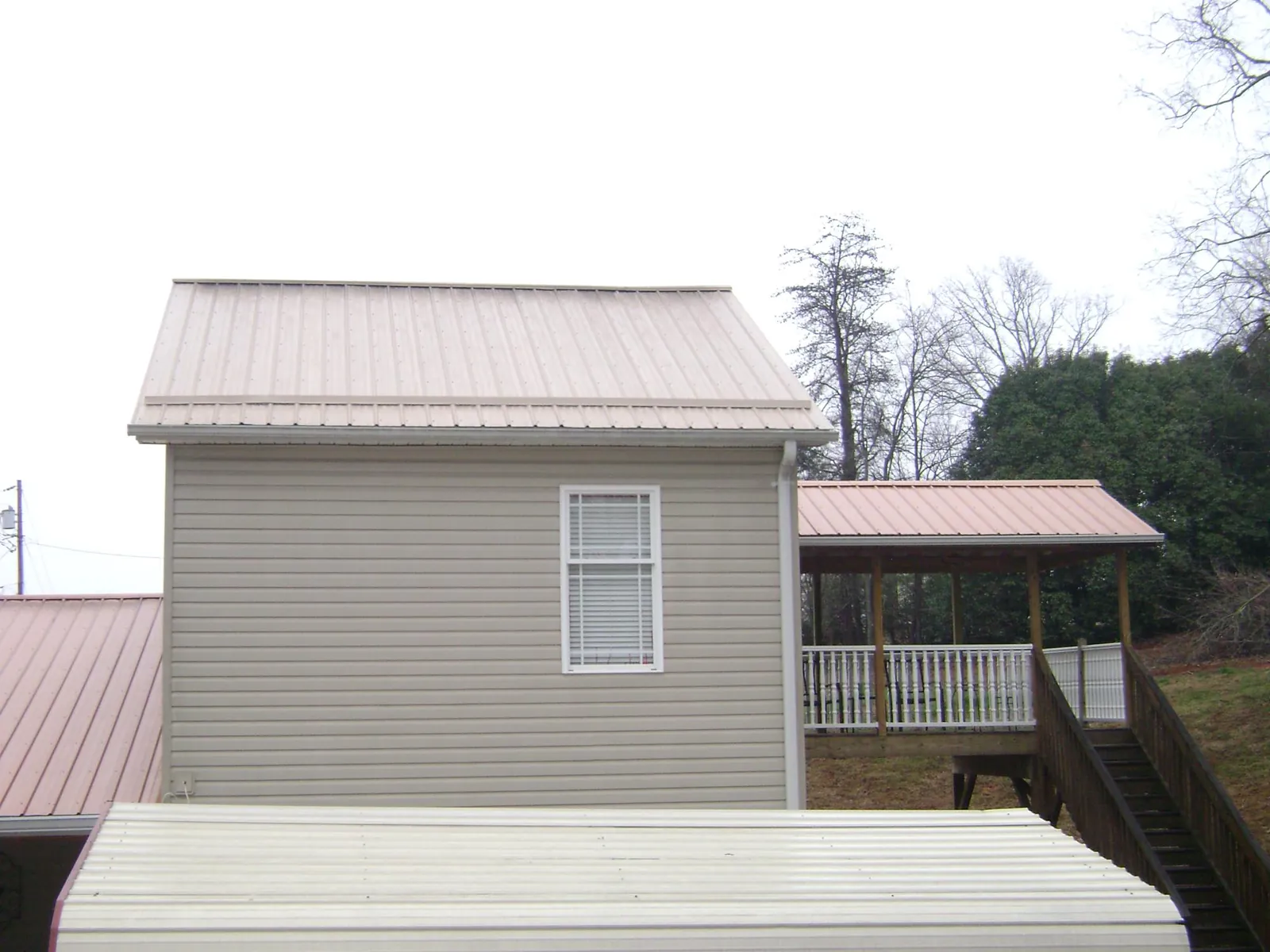 Tan metal roofs on a two story addition and attached porch, from a Roof Replacement job in Rimrock