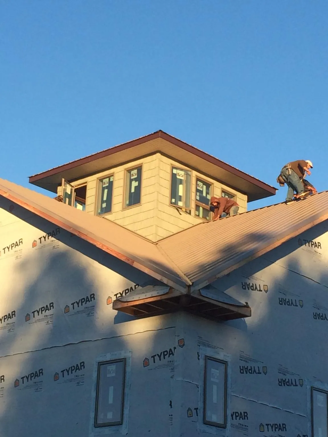 Roofers working around a rooftop cupola on a new metal roof at sunset — Roof Waterproofing in Rimrock by Roofing Brothers